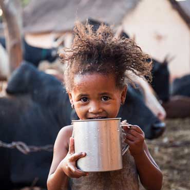 Small girl drinking water from mug