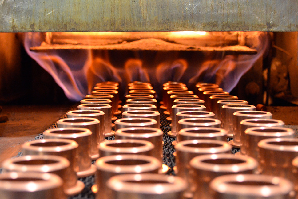 Carbon steel powdered metal parts entering a sintering furnace